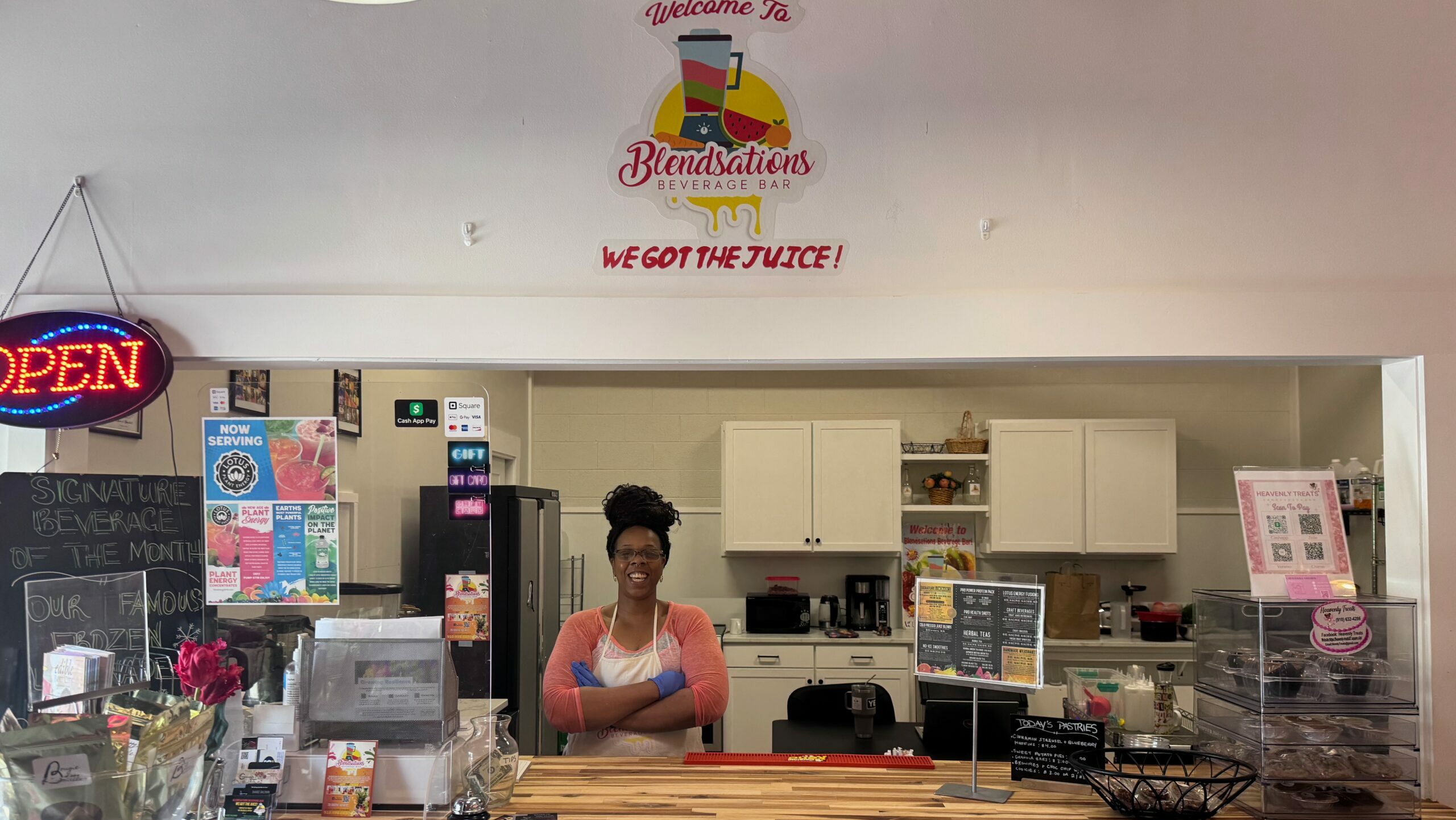 Sharee Baldwin at Blendsations, her new beverage bar. She's standing behind the county wearing an apron with her arms crossed.