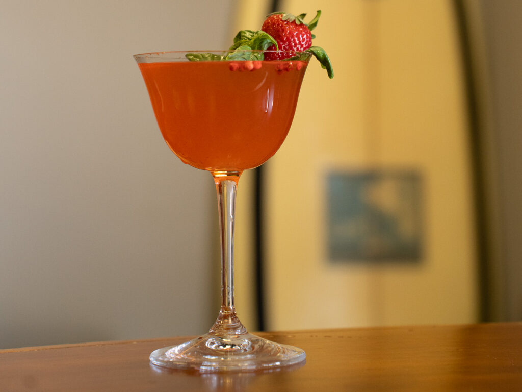 pink cocktail on a bar with a yellow surf board in the backgroud