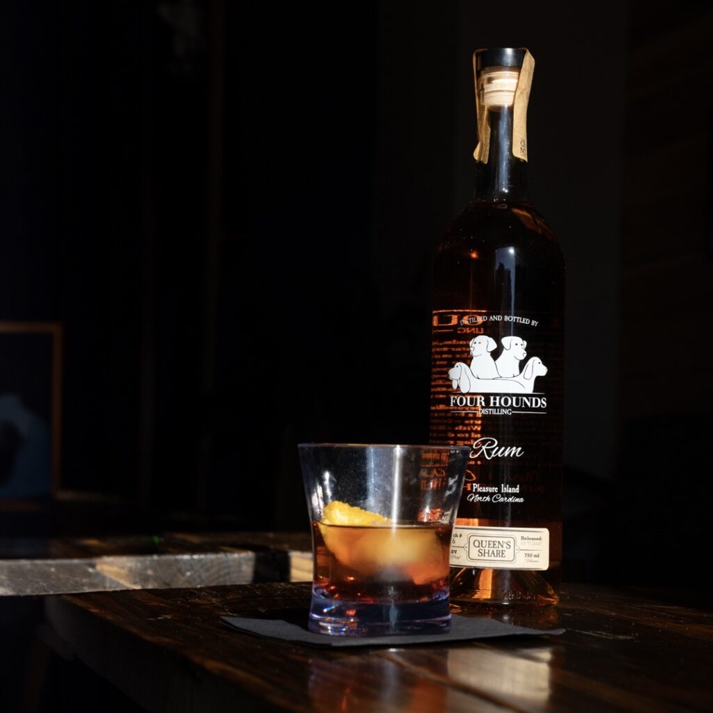 cocktail with orange twist in front of a bottle of rum