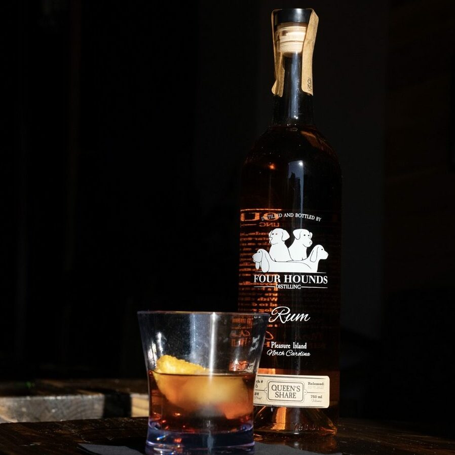 cocktail with orange twist in front of a bottle of rum