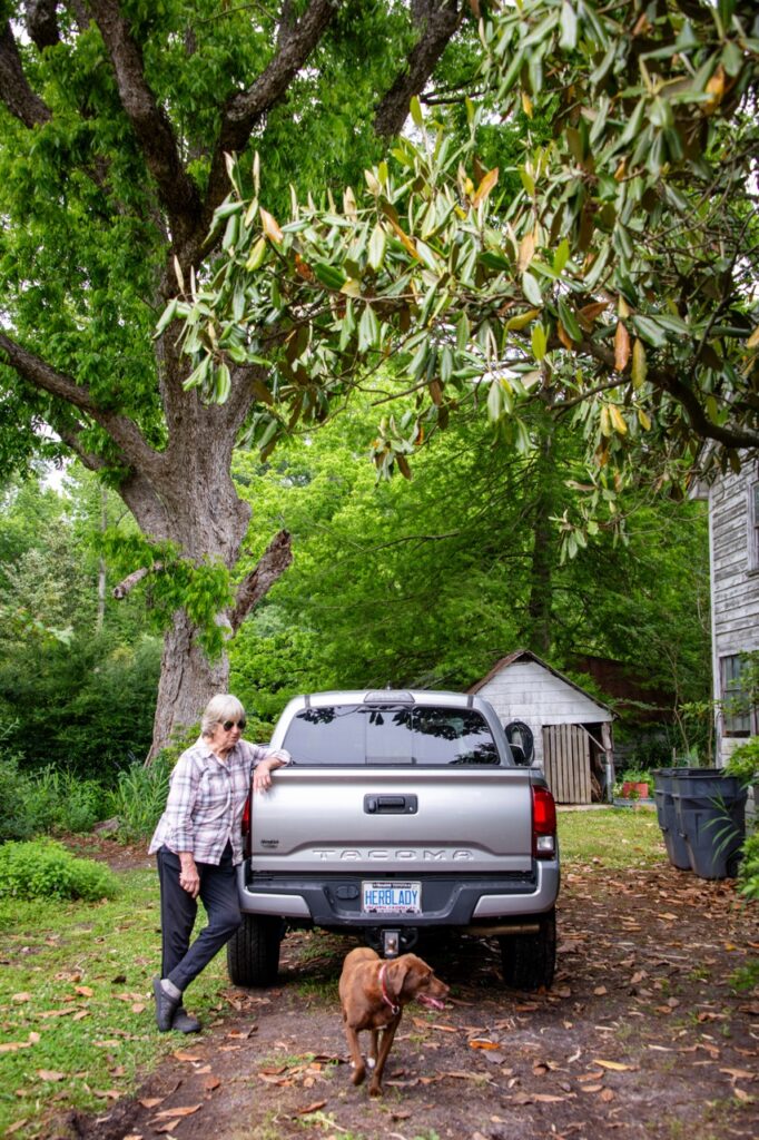woman next to silver pick up truck and dog