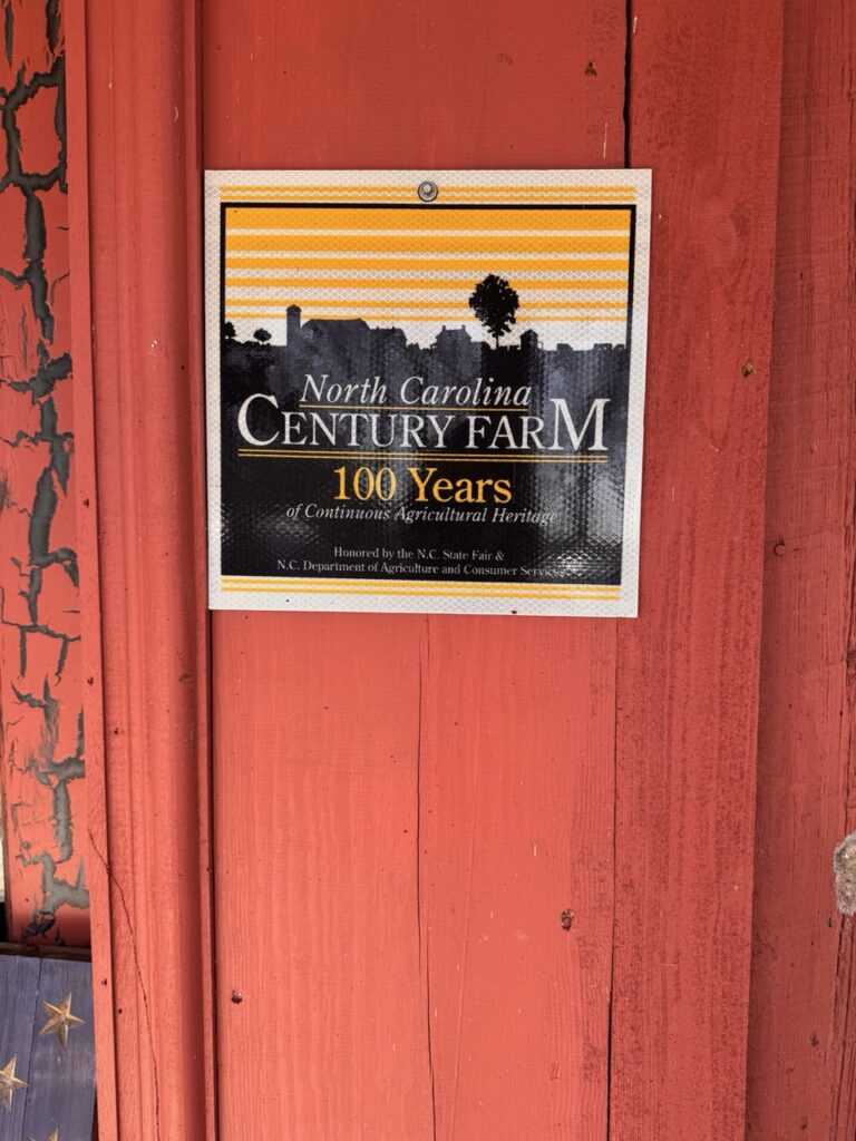 red wooden door with a sign saying century farm