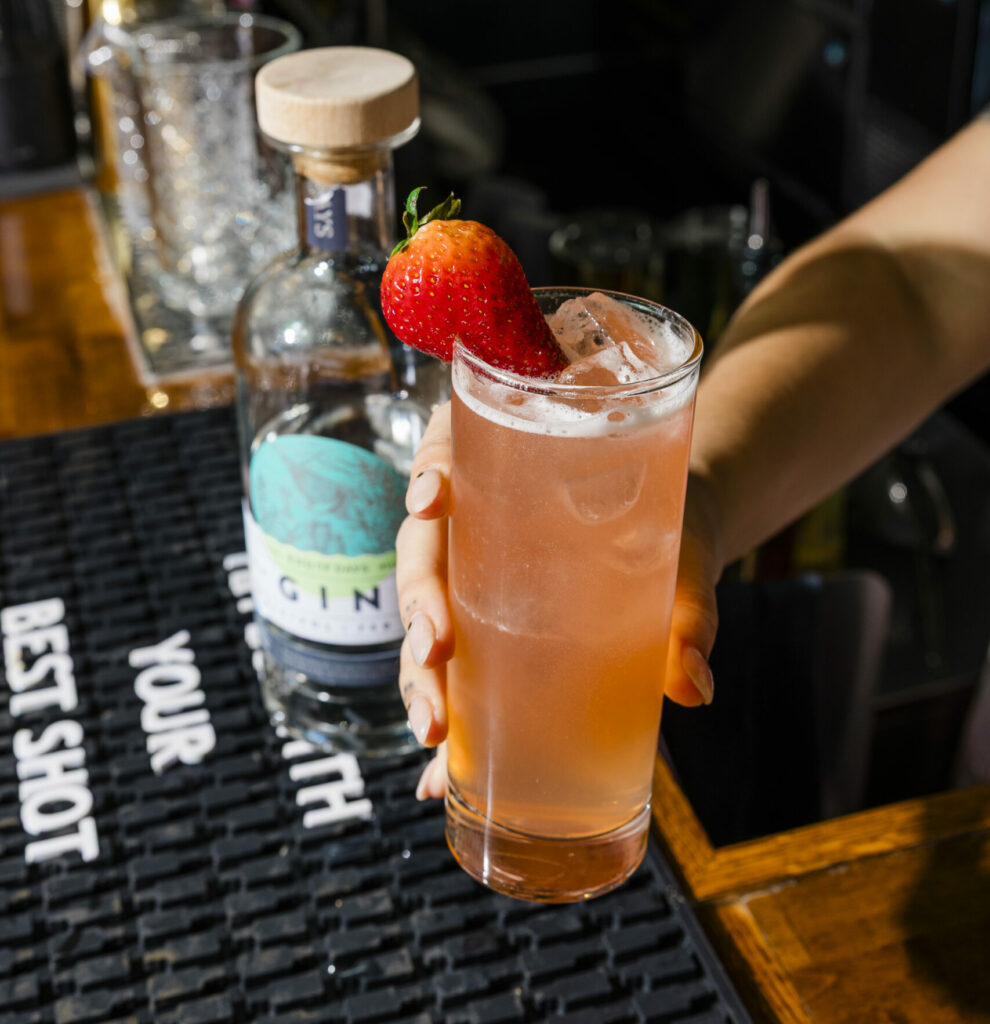 pink cocktail in a glass with strawberry garnish