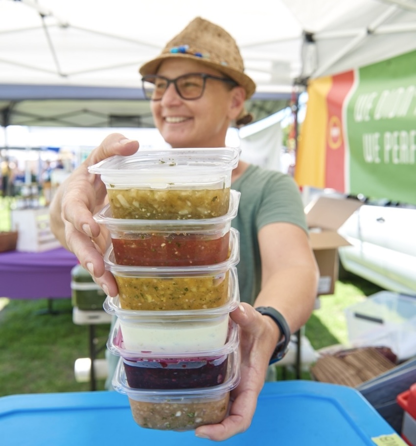 woman holding a stack of boxes of RAW salsa