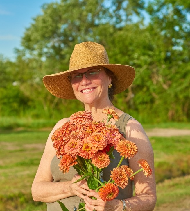 woman in straw hat holding salmon colored flowers